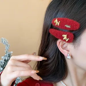 Dettaglio di un fermaglio per capelli in lana rossa festiva con ciondolo a cavallo