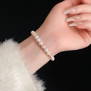 Detailed close-up of a multi-colored pearl stretch bracelet worn on a female wrist.