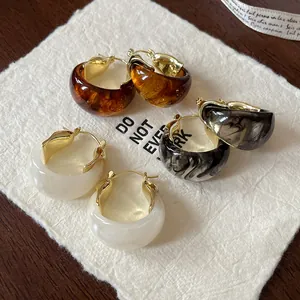 Close-up view of vintage marbled U-shaped resin hoop earrings in assorted colors