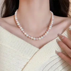 Close-up of elegant multi-color pearl necklace on model wearing cream knit sweater.