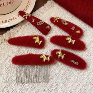 Primo piano di fermagli per capelli in lana rossa con ciondoli a cavallo dorati 'Handmade'