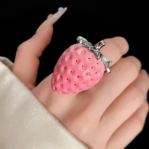 Macro view of a pink resin strawberry ring with realistic texture and silver stem.