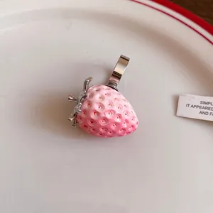 Close-up detail of realistic pink resin strawberry pendant with silver metal bail