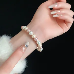 Detailed close-up showing a multi-colored pearl stretch bracelet worn on a woman's slender wrist