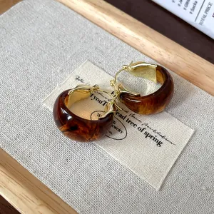 Close-up of vintage U-shaped hoop earrings with tortoiseshell resin and gold finish