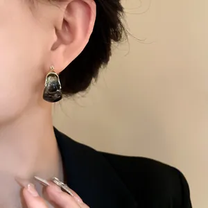 Close-up view of retro marbled U-shaped hoop earrings featuring elegant gold-toned metal accents