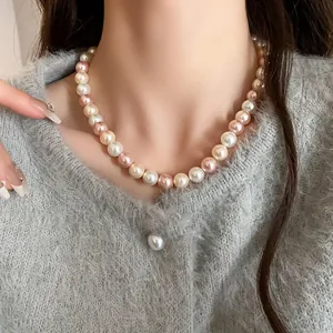 Detail view of a multicolor pearl necklace featuring pink and white pearls on a model.