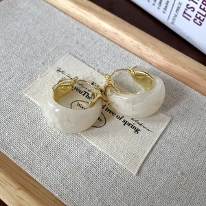 Close-up shot of minimalist marbled U-shaped hoop earrings with elegant gold-tone accents.