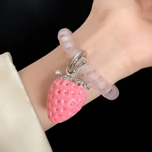 Close-up of a pink resin strawberry charm on a frosted clear spiral hair tie bracelet