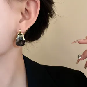 Detailed view of vintage smoky grey marbled U-shaped basket earrings on an Asian model