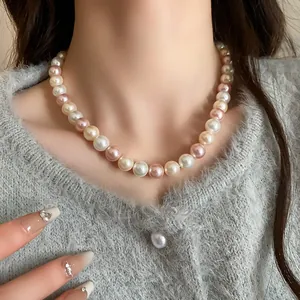 Detail shot of an elegant mixed-color pearl necklace worn with a grey cardigan
