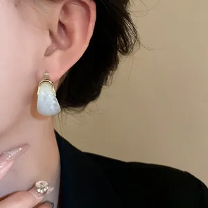 Close-up of elegant U-shaped resin earrings with marble pattern on model's ear