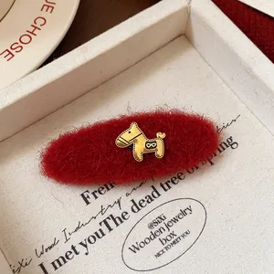 Dettaglio di un fermaglio per capelli in mohair rosso con un charm a cavallo oro.