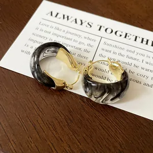 Close-up detail of vintage marble pattern U-shape hoop earrings with gold-tone metal