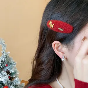 Primo piano di un fermaglio natalizio in lana rossa con ciondolo a forma di cavallo d'oro