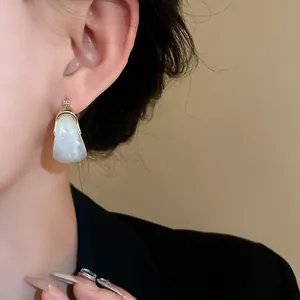 Close-up of marbled U-shaped basket earrings with vintage gold-tone finish on model