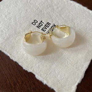 Macro view of retro marbled U-shaped hoop earrings with polished gold hardware detail.