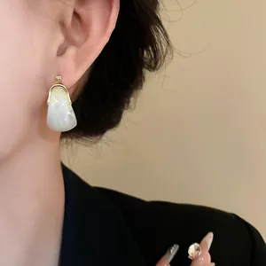 Close-up of vintage U-shaped basket earrings with marbled white stone inlay on model