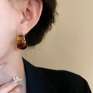 Close-up of amber smudge U-shaped earring on ear, retro autumn winter style detail
