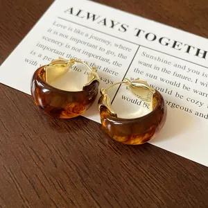 Detailed shot of retro amber tortoiseshell U-shaped hoop earrings with gold accents.