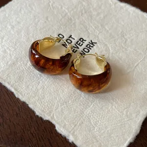 Macro detail of vintage U-shaped basket hoop earrings with brown marble texture