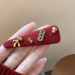Dettaglio macro di un fermaglio per capelli in lana rossa con ciondoli dorati vintage