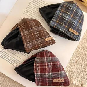 Three retro plaid fabric and leather hair claw clips displayed elegantly on an open book