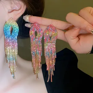 Dettaglio ravvicinato di lunghi orecchini a nappa con strass arcobaleno su modella