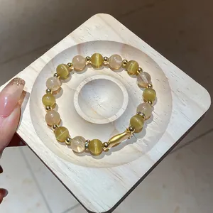 Primo piano di un elegante bracciale di perle con pietre occhio di gatto e accenti dorati