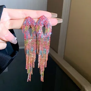 Dettaglio di orecchini lunghi con nappe di strass caratterizzati da un gradiente brillante