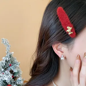 Dettaglio di un fermaglio per capelli in lana rossa con ciondolo a cavallo dorato.
