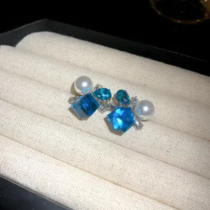 Primer plano de elegantes pendientes con cristales azules y perlas blancas en un joyero de lujo