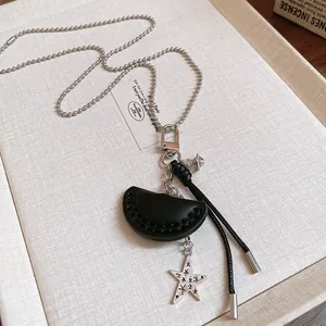Macro detail of a holiday style necklace featuring black leather shell and metal star pendants
