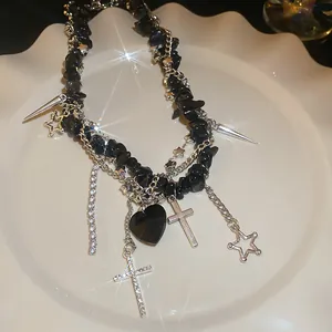 Detailed view of a gothic black stone necklace with silver cross and heart charms on a plate