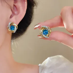 Primer plano de elegantes pendientes dorados irregulares con piedra azul y strass
