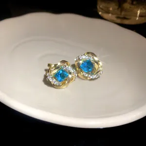 Detalle de elegantes pendientes dorados con piedras preciosas azules y cristales.