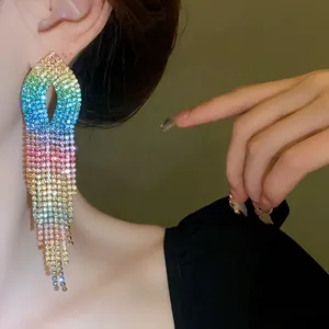 Dettaglio di lunghi orecchini a nappa con strass arcobaleno e finitura sfumata