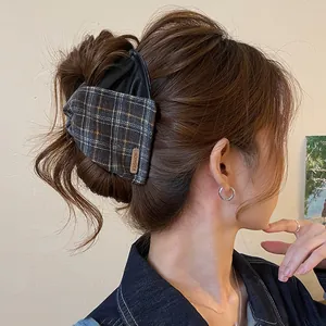 Detail view of a retro plaid and leather hair claw clip worn on a messy bun hairstyle