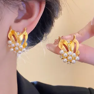 Makroaufnahme von detaillierten goldenen Weizenohrringen mit Perlen und Zirkoniasteinen