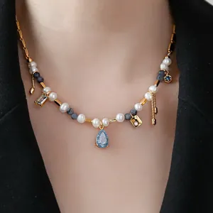 Close-up of a handmade beaded necklace with freshwater pearls and a blue teardrop stone.