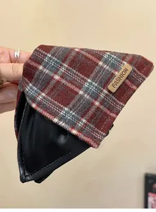Macro view of vintage plaid fabric and black leather texture on a shark hair clip.