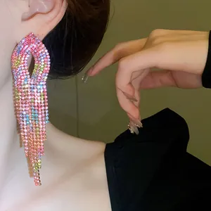 Dettaglio macro dell'orecchino a nappa con strass sfumati colorati sulla modella