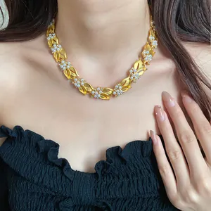 Nahaufnahme einer eleganten goldenen Weizenblatt-Halskette mit Perlen und Zirkonia.