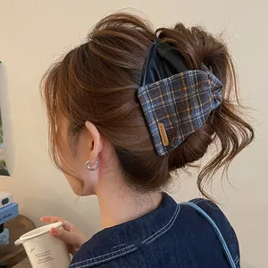 Detail view of a vintage leather and plaid fabric hair claw clip on brunette hair