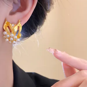 Nahaufnahme eines eleganten Weizen-Ohrrings aus Gold mit glänzenden Perlen und Zirkonia.