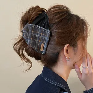 Close-up of a retro checkered hair claw clip with leather and fabric stitching design