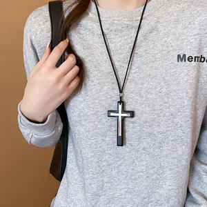 Close-up view of a double-layered cross pendant necklace worn on a grey sweatshirt