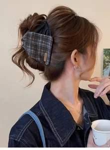Detailed view of a vintage plaid and leather bow hair claw clip worn by a fashion model