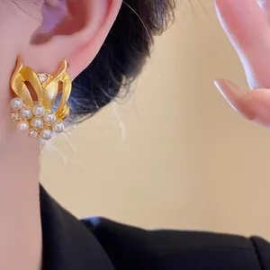 Detailansicht von goldenen Vintage-Ohrringen mit Perlen und Zirkonia an einem Modell-Ohr