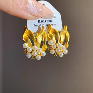 Detailansicht goldener Vintage-Ohrringe mit Perlen und funkelnden Zirkoniasteinen
